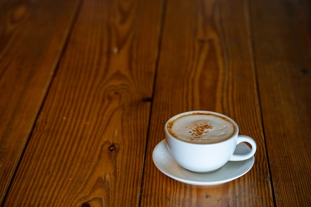 Tasse Cappuccino auf strukturiertem Holztisch mit Textfreiraum