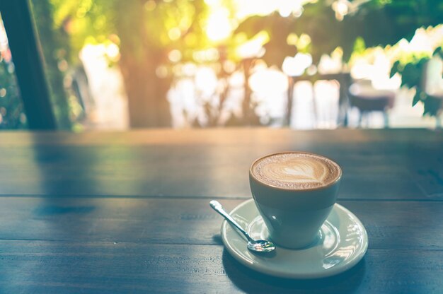 Foto tasse cappuccino-kaffee auf holztisch und schokolade im vintage-lebensstil auf weißer tasse