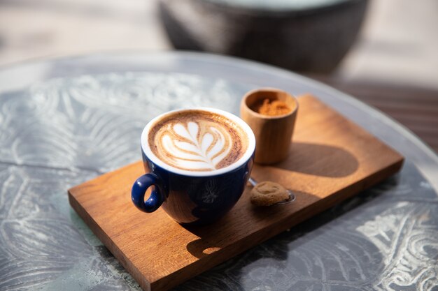 Tasse cappuccino mit latte art mit löffel auf holzuntergrund