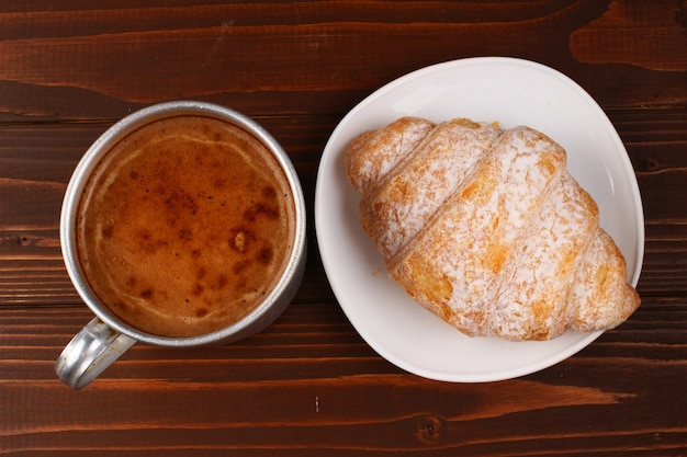 Tasse Cappuccino und Croissant auf dem Tisch