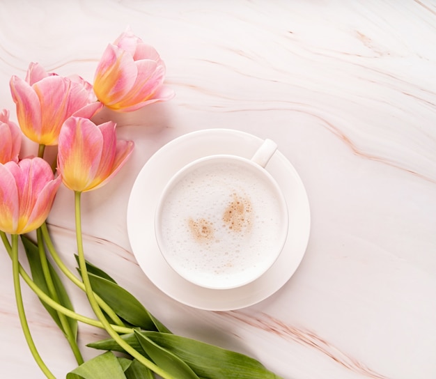 Tasse Cappuccino und rosa Tulpen Draufsicht auf Marmorhintergrund