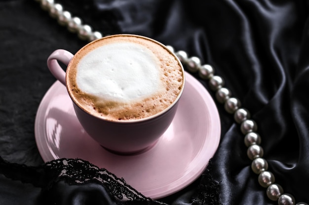 Tasse Cappuccino zum Frühstück mit Satin- und Perlenschmuck Hintergrund Bio-Kaffee mit laktosefreier Milch im Pariser Café für Luxus-Vintage-Urlaubsmarke