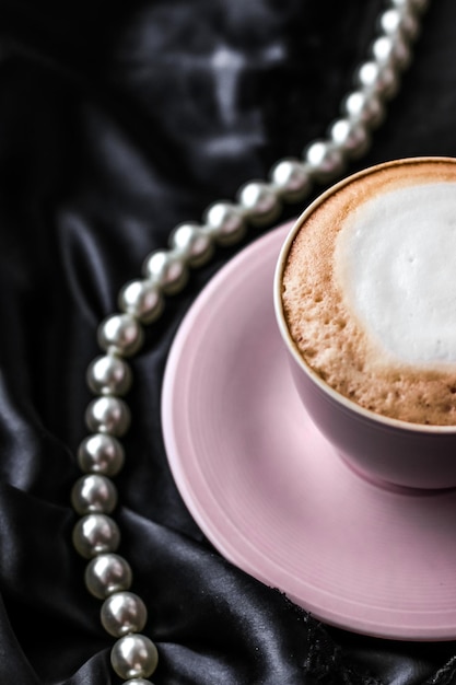 Tasse Cappuccino zum Frühstück mit Satin- und Perlenschmuck Hintergrund Bio-Kaffee mit laktosefreier Milch im Pariser Café für Luxus-Vintage-Urlaubsmarke