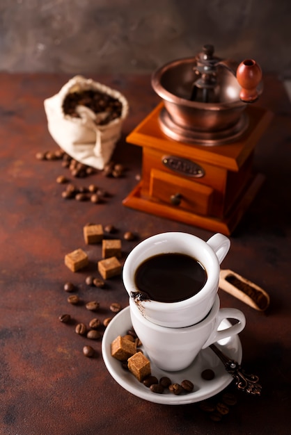 Tasse dampfenden heißen Kaffee mit Kaffeebohnen, Kaffeemühle und Kaffeebohnentasche