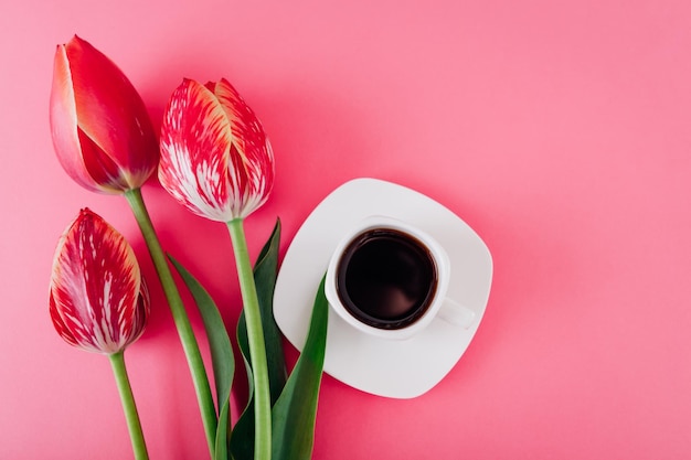 Tasse Espressokaffee und frische Tulpen auf rosa Hintergrund guten Morgen