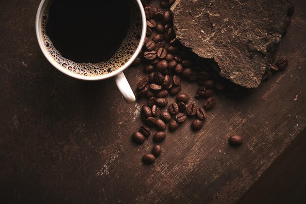 Tasse frisch gebrühte geröstete Kaffeebohnen auf braunem Hintergrund