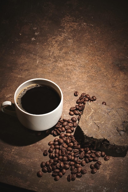 Tasse frisch gebrühte geröstete Kaffeebohnen auf braunem Hintergrund