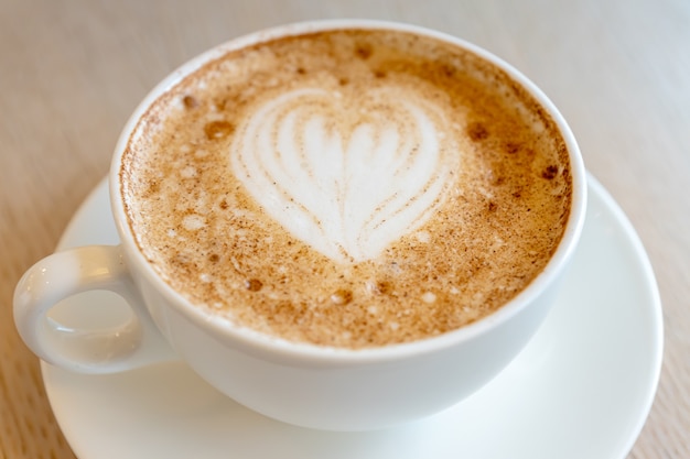 Tasse frisch gebrühten Cappuccino mit Latte Art Schaum auf einem Tisch der Cafeteria.