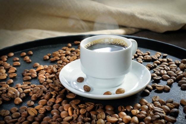 Tasse frischer Kaffee und geröstete Kaffeebohnen Nahaufnahme Hintergrund Textur guten Morgen Konzept