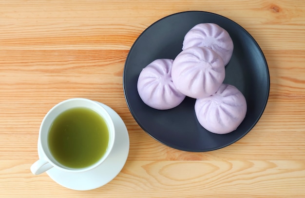 Tasse grüner Tee mit einem Teller Taro gedämpfte Brötchen auf Holztisch