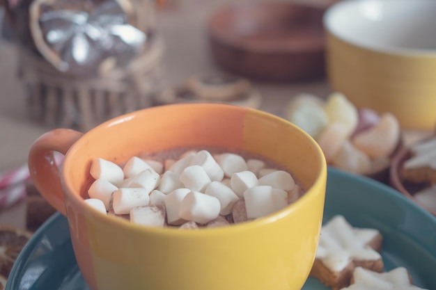 Tasse heiße Schokolade mit Marshmallow auf dem Hintergrund von Schokolade und Zimt. Gemütlicher Weihnachts-Zuhause-Urlaub