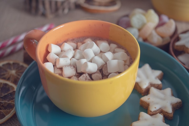 Tasse heiße Schokolade mit Marshmallow auf dem Hintergrund von Schokolade und Zimt. Gemütlicher Weihnachts-Zuhause-Urlaub