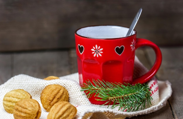 Tasse heiße Schokolade mit Weihnachtsbaumzweigen und Plätzchen auf dem Tisch