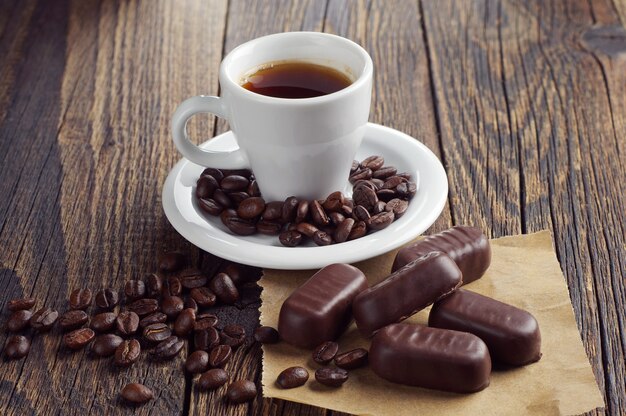 Tasse heißen Kaffee mit Pralinen auf dunklem Holztisch