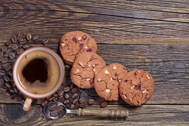 Tasse heißen Kaffee mit Schokoladenkeksen auf altem Holzhintergrund, Ansicht von oben