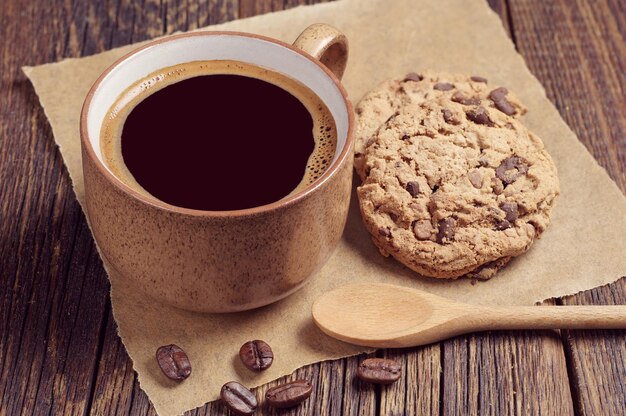 Tasse heißen Kaffee mit Schokoladenkeksen auf dunklem Holztisch