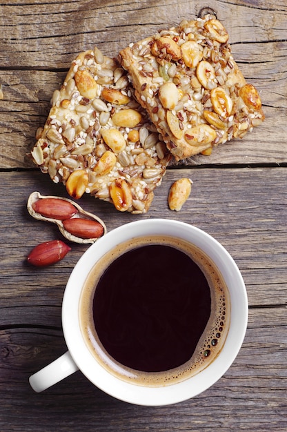 Tasse heißen Kaffee und Kekse mit Nüssen auf dunklem Holztisch, Ansicht von oben