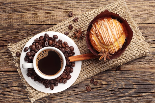 Tasse heißen Kaffee und köstlichen Cupcake auf altem Holztisch Draufsicht
