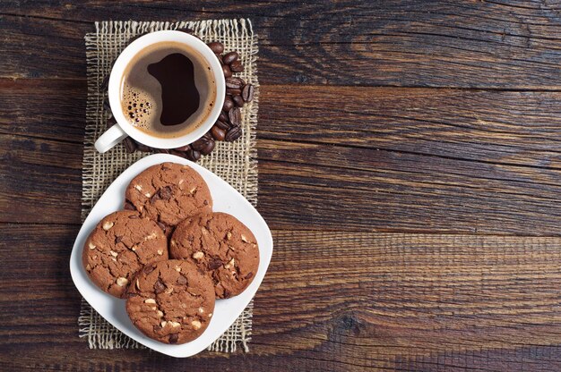 Tasse heißen Kaffee und Schokoladenkekse mit Nüssen auf Holztisch, Draufsicht