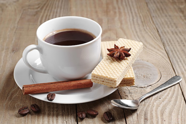 Tasse heißen Kaffee und süße Waffeln auf rustikalem Holztisch