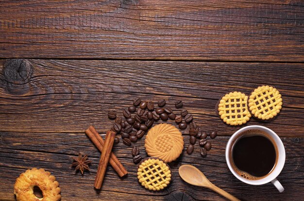 Tasse heißen Kaffee und verschiedene süße Kekse auf dunklem Holztisch Draufsicht Platz für Text