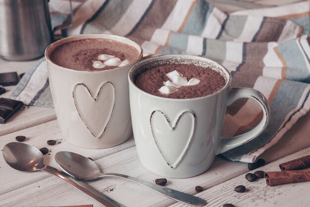 Tasse heißen Kakao mit Marshmallows und Zimtstangen