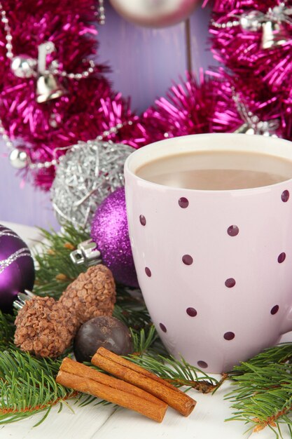 Tasse heißen Kakao mit Pralinen und Weihnachtsschmuck auf dem Tisch auf Holzuntergrund