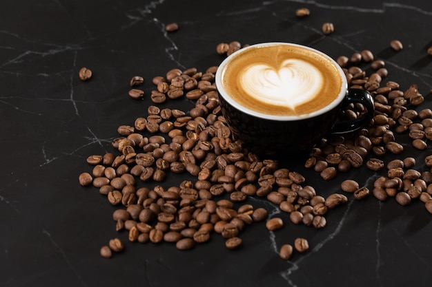 Tasse heißen Latte-Kaffee mit schöner Milchschaum-Latte-Art-Textur mit Kaffeebohne auf schwarzem Marmorhintergrund. Draufsicht, Kopienraum. Werbung für Café-Menü. Speisekarte des Cafés.