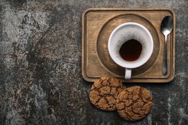 Tasse heißen schwarzen Kaffee auf hölzernem Schreibtisch mit Keksen