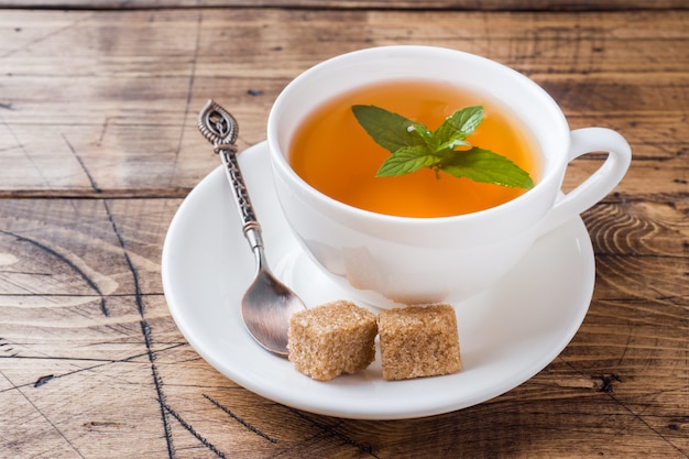 Tasse heißen Tee mit Minze und braunem Zucker