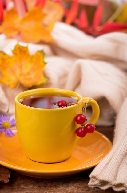 Tasse heißen Tee und Herbstlaub, auf braunem Hintergrund