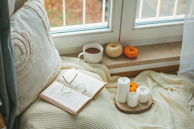 Tasse heißer Kakao auf einem Rattan-Tablett in der Nähe des Fensters ein Plaid ein Kissen Kürbisse Gemütliches Öko-Dekor für zu Hause Herbststimmung