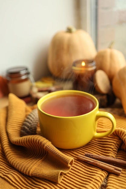 Tasse heißer Tee Pullover Kerze und Kürbisse auf der Fensterbank Herbstatmosphäre