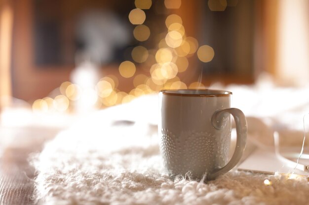 Foto tasse heißgetränk auf fuzzy-teppich vor verschwommenem hintergrund platz für text winterabend