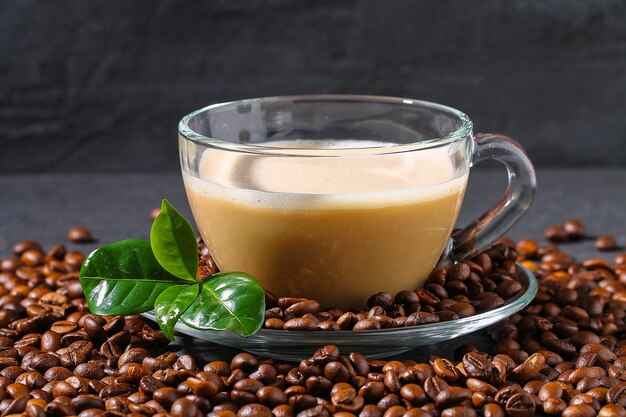 Tasse Kaffee auf einem grauen Tisch mit Kaffeebohnen und Kaffeeblättern