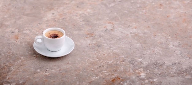 Tasse Kaffee auf grauem Hintergrund Einzelne Tasse Kaffee mit Sahne und Schokoladenstückchen