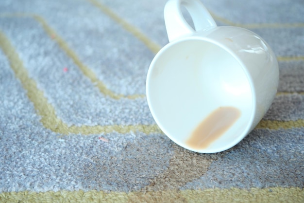 Tasse Kaffee auf grauem Teppich verschüttet