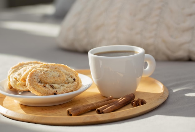 Tasse Kaffee auf Holztablett auf dem Bett im gemütlichen Schlafzimmer