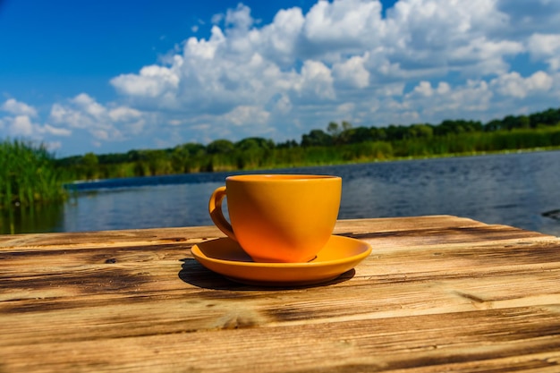 Tasse Kaffee auf Holztisch am Flussufer