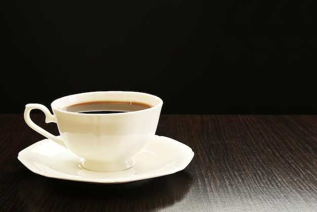 Tasse Kaffee auf Holztisch auf dunklem Hintergrund