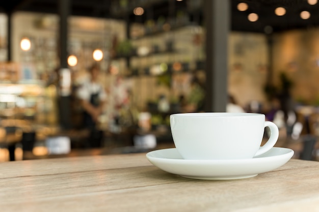 Tasse Kaffee auf Holztisch im Café mit verwischt.