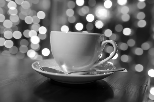 Tasse Kaffee auf Holztisch im Café verwischen Lichter auf Hintergrund