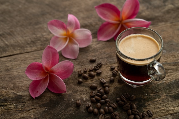 Tasse Kaffee auf Holztisch mit Frangipani-Blume.