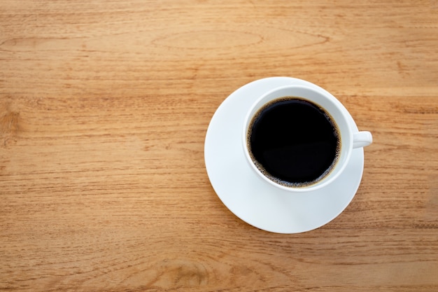 Tasse Kaffee auf Holztisch.