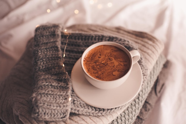 Tasse Kaffee auf Strickwaren im Bett hautnah. Winterferienzeit. Guten Morgen.