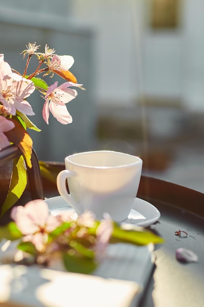 Tasse Kaffee, Blumen und Notizbuch auf dem kleinen schwarzen Tisch