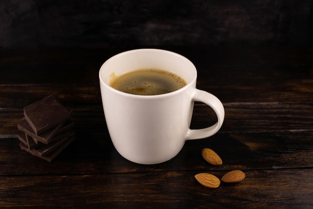 Tasse Kaffee Cappuccino Mandeln und dunkle Schokolade auf dunklem Holzhintergrund
