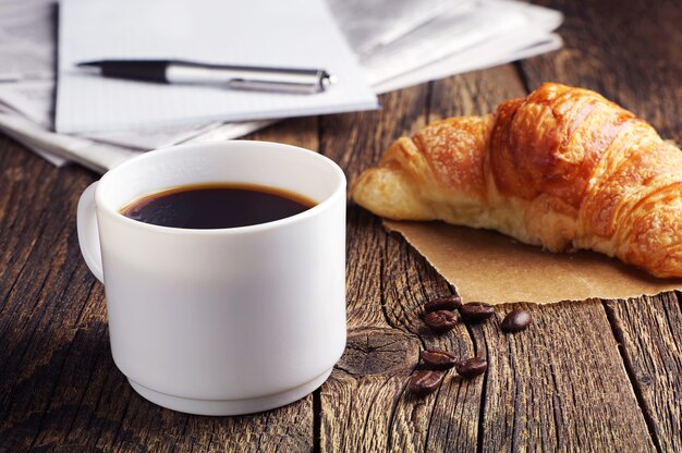 Tasse Kaffee, Croissant und Zeitung