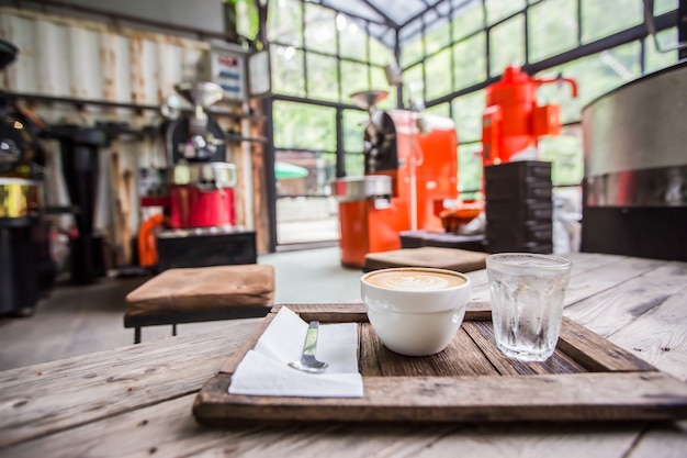 Tasse kaffee im shop mit kaffeeröstermaschinen-unschärfehintergrund