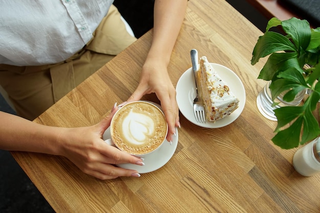 Tasse Kaffee in einem Café und Hände eines Mädchens Nahaufnahme der Hände einer Frau, die mit einer Tasse Kaffee in einem Café sitzen